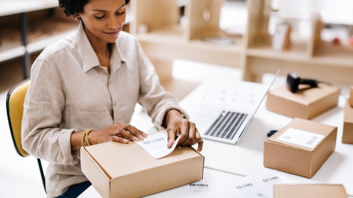 A Woman in a warehouse examines a return envelope.