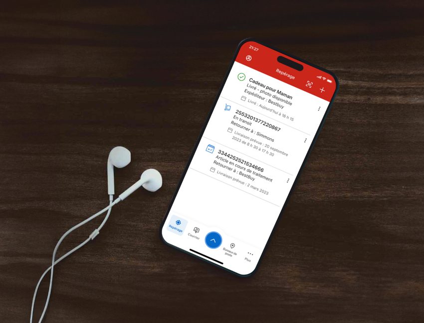 Un cellulaire est utilisé pour suivre des envois dans l’appli de Postes Canada. Des écouteurs sont posés à côté du cellulaire